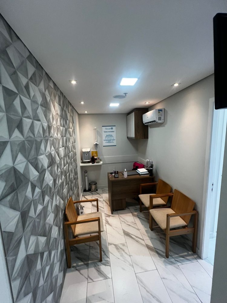 Recepção com parede cinza em 3D, poltronas de madeira e mesa de atendimento